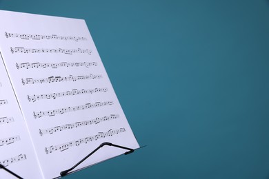 Photo of Note stand with music sheets on light blue background, closeup. Space for text