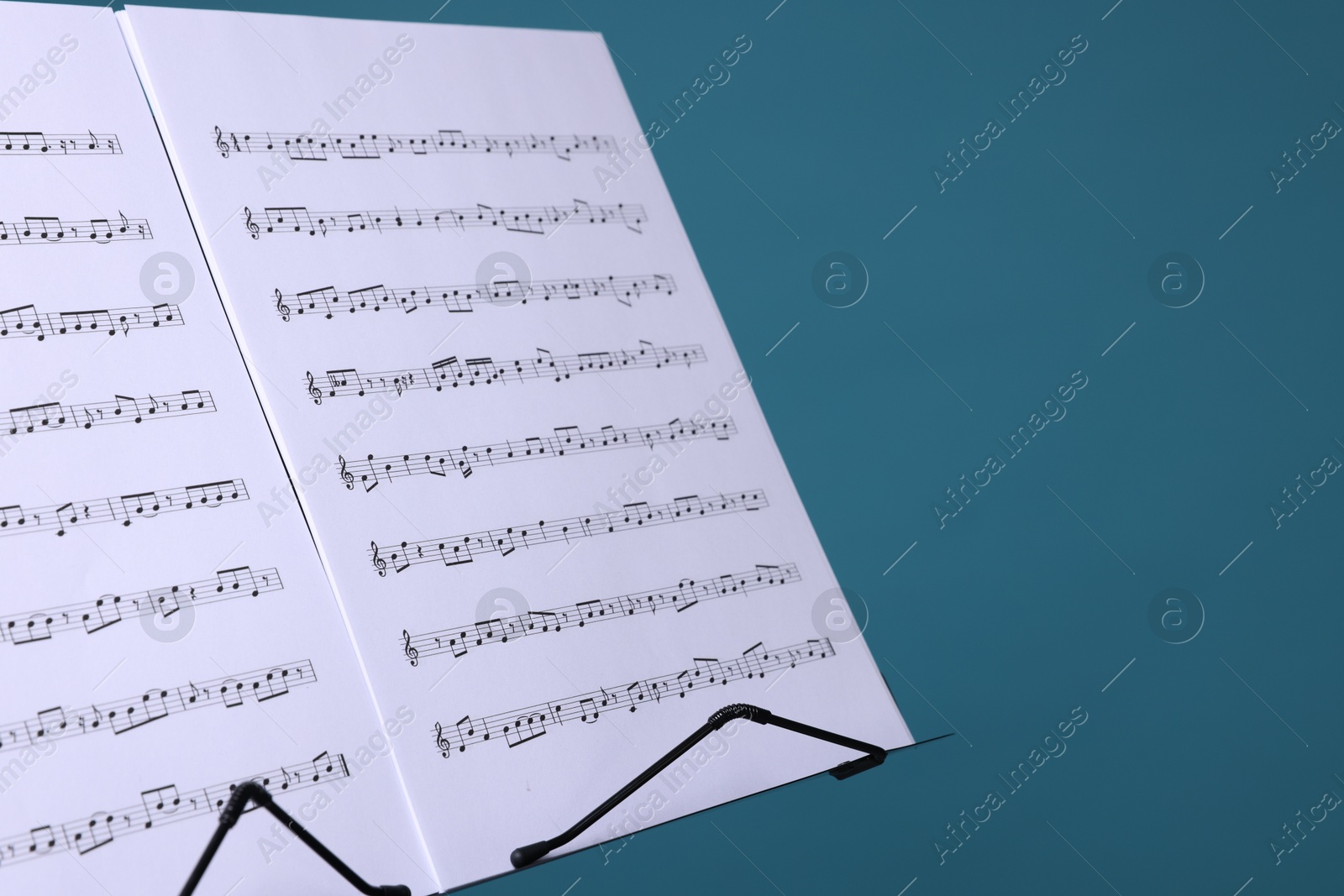 Note stand with music sheets on light blue background, closeup. Space for text Photo of Note stand with music sheets on light blue background, closeup. Space for text