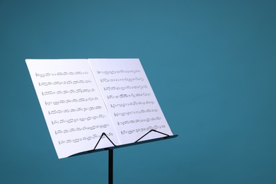Photo of Note stand with music sheets on light blue background, space for text