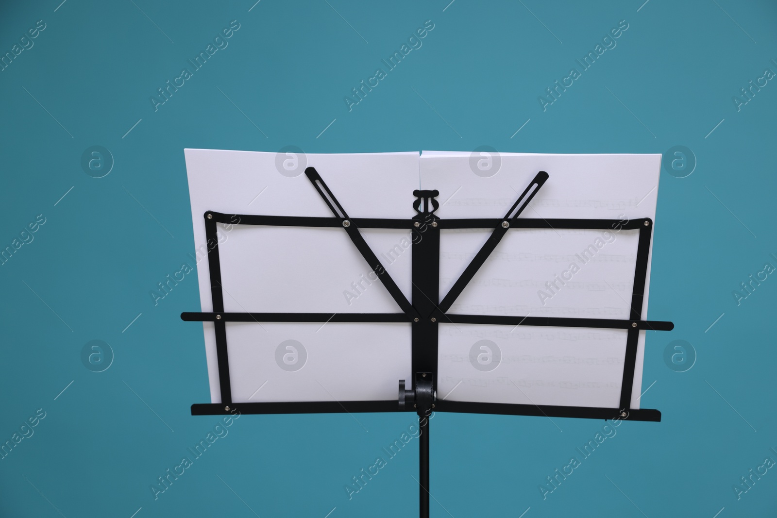 Note stand with music sheets on light blue background Photo of Note stand with music sheets on light blue background