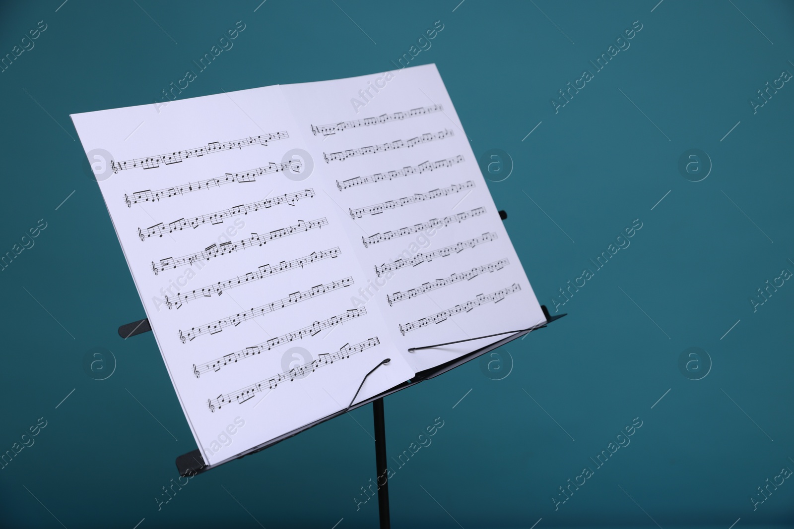 Note stand with music sheets on light blue background, closeup. Space for text Photo of Note stand with music sheets on light blue background, closeup. Space for text
