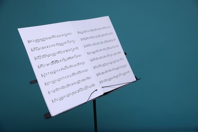 Photo of Note stand with music sheets on light blue background, closeup. Space for text
