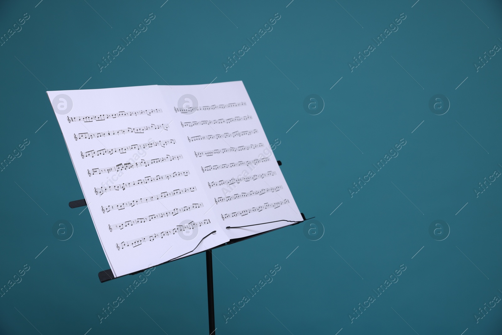 Note stand with music sheets on light blue background, space for text Photo of Note stand with music sheets on light blue background, space for text