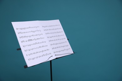 Photo of Note stand with music sheets on light blue background, space for text