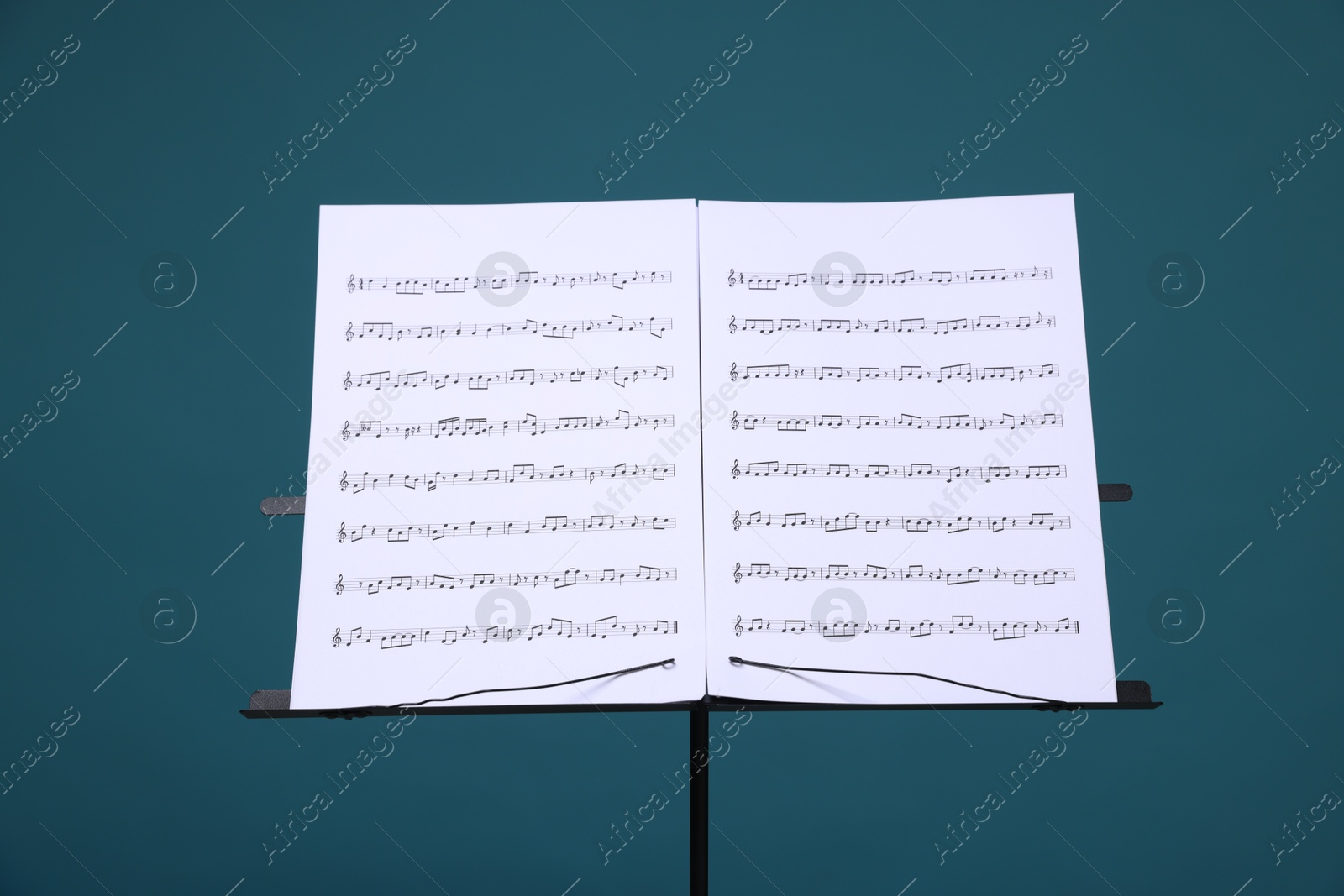 Note stand with music sheets on light blue background Photo of Note stand with music sheets on light blue background