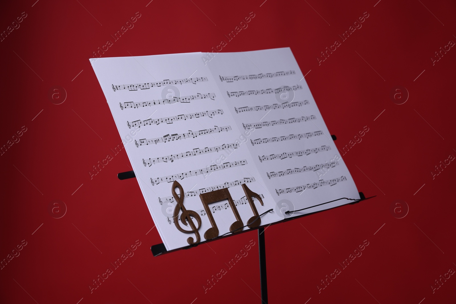 Stand with music sheets and wooden notes on red background, closeup Photo of Stand with music sheets and wooden notes on red background, closeup