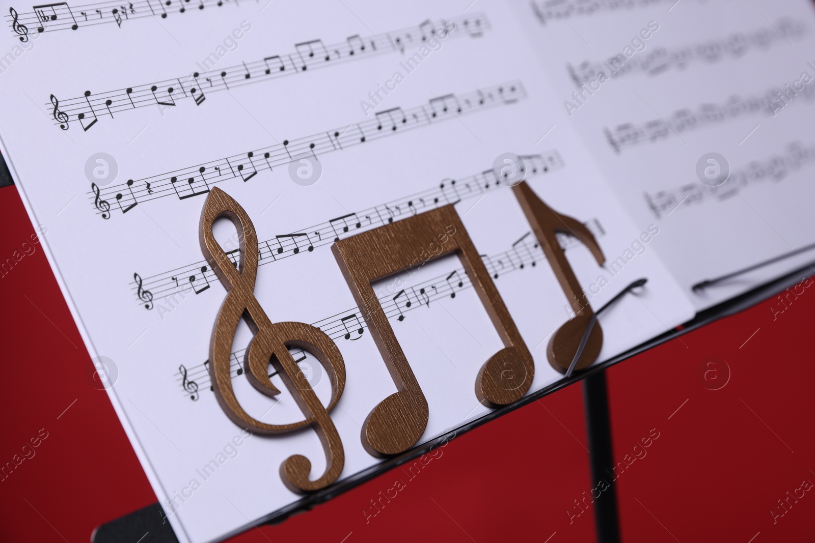 Stand with music sheets and wooden notes on red background, closeup Photo of Stand with music sheets and wooden notes on red background, closeup