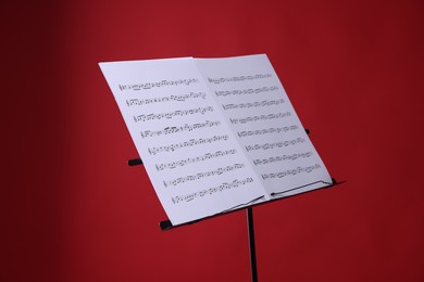 Photo of Note stand with music sheets on red background