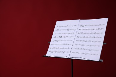 Photo of Note stand with music sheets on red background, space for text