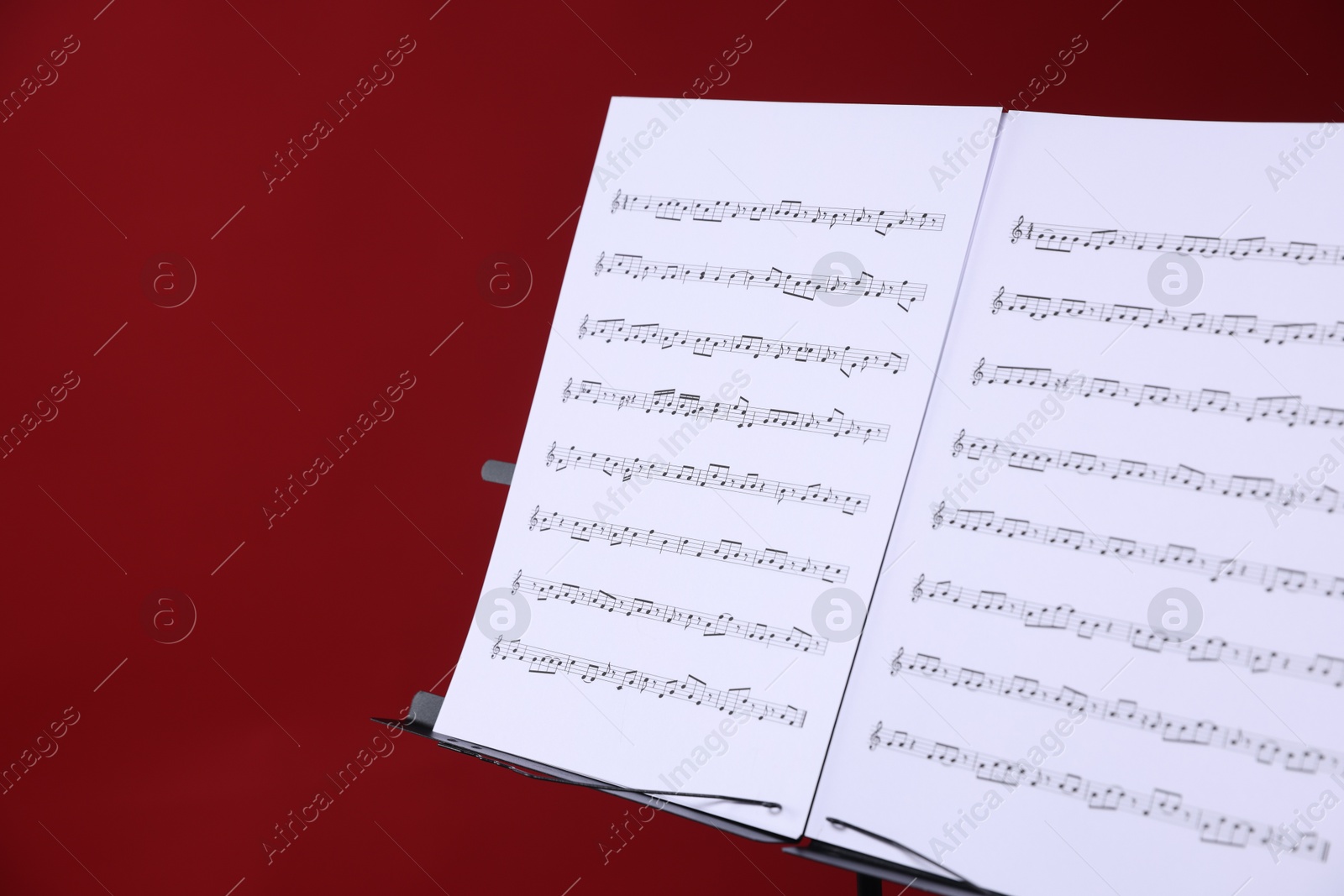 Note stand with music sheets on red background, closeup. Space for text Photo of Note stand with music sheets on red background, closeup. Space for text