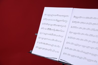 Photo of Note stand with music sheets on red background, closeup. Space for text