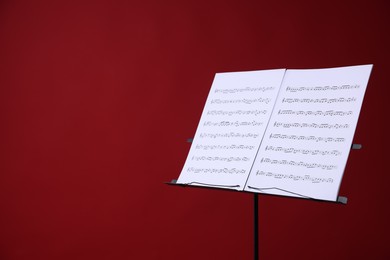 Photo of Note stand with music sheets on red background, space for text