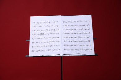 Photo of Note stand with music sheets on red background