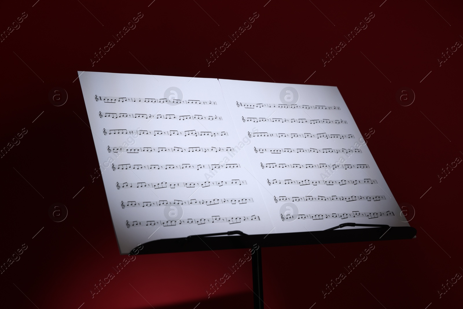 Note stand with music sheets on dark red background, closeup Photo of Note stand with music sheets on dark red background, closeup
