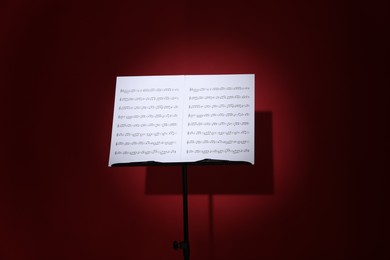 Photo of Note stand with music sheets on dark red background
