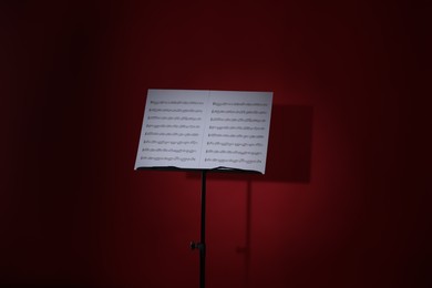 Photo of Note stand with music sheets on dark red background