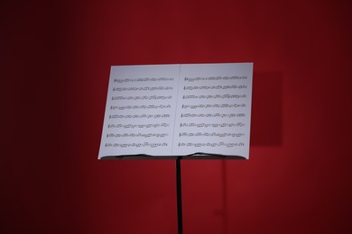 Photo of Note stand with music sheets on red background