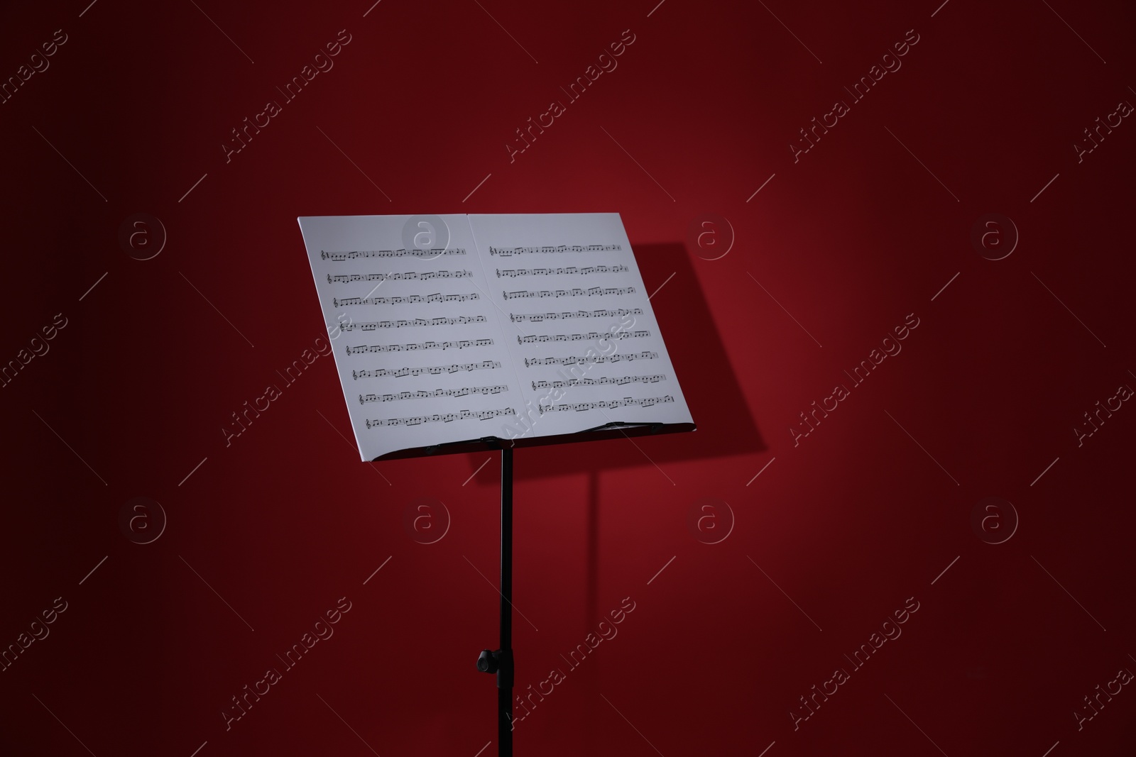 Note stand with music sheets on red background Photo of Note stand with music sheets on red background