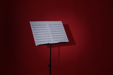 Photo of Note stand with music sheets on red background