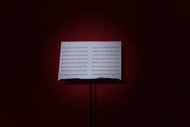 Photo of Note stand with music sheets on dark red background