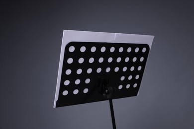 Photo of Note stand with music sheets on grey background, closeup