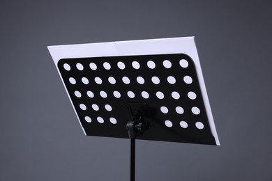 Photo of Note stand with music sheets on grey background, closeup