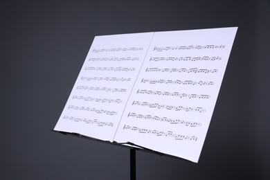 Photo of Note stand with music sheets on grey background, closeup