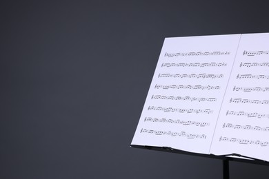 Photo of Note stand with music sheets on grey background, closeup. Space for text