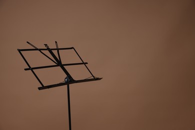 Photo of One empty note stand on dark beige background, space for text