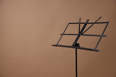 Photo of One empty note stand on dark beige background, space for text