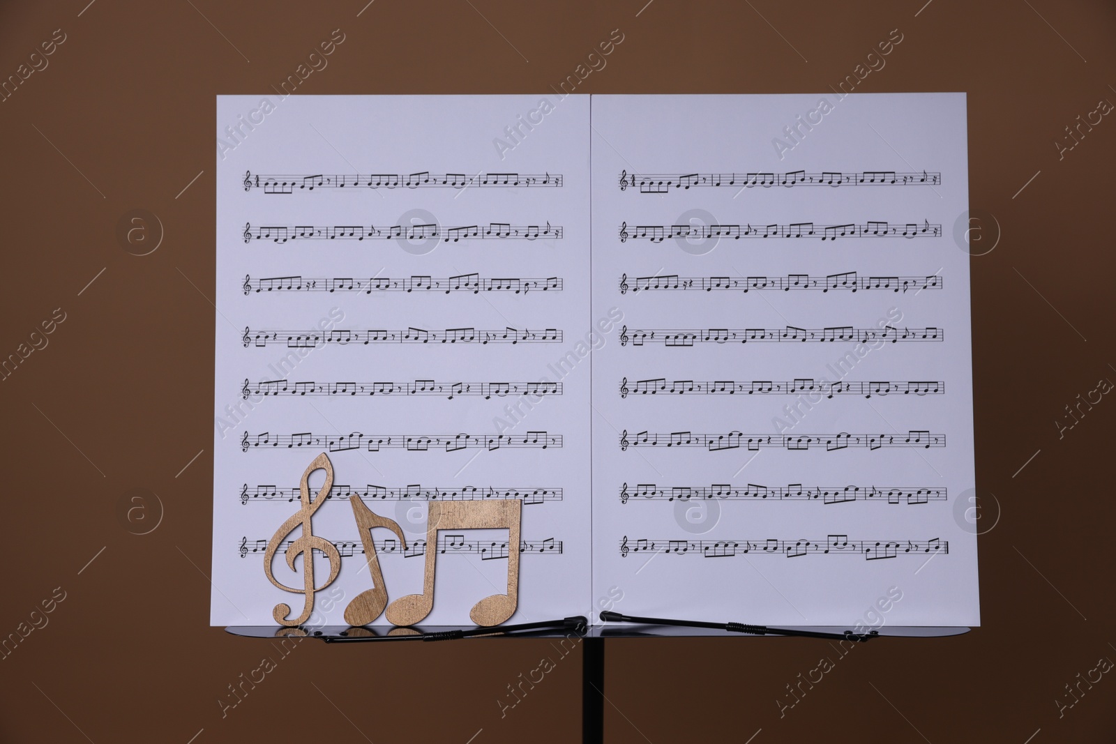 Stand with music sheets and wooden notes on dark beige background Photo of Stand with music sheets and wooden notes on dark beige background