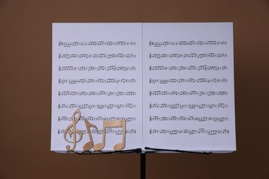Photo of Stand with music sheets and wooden notes on dark beige background