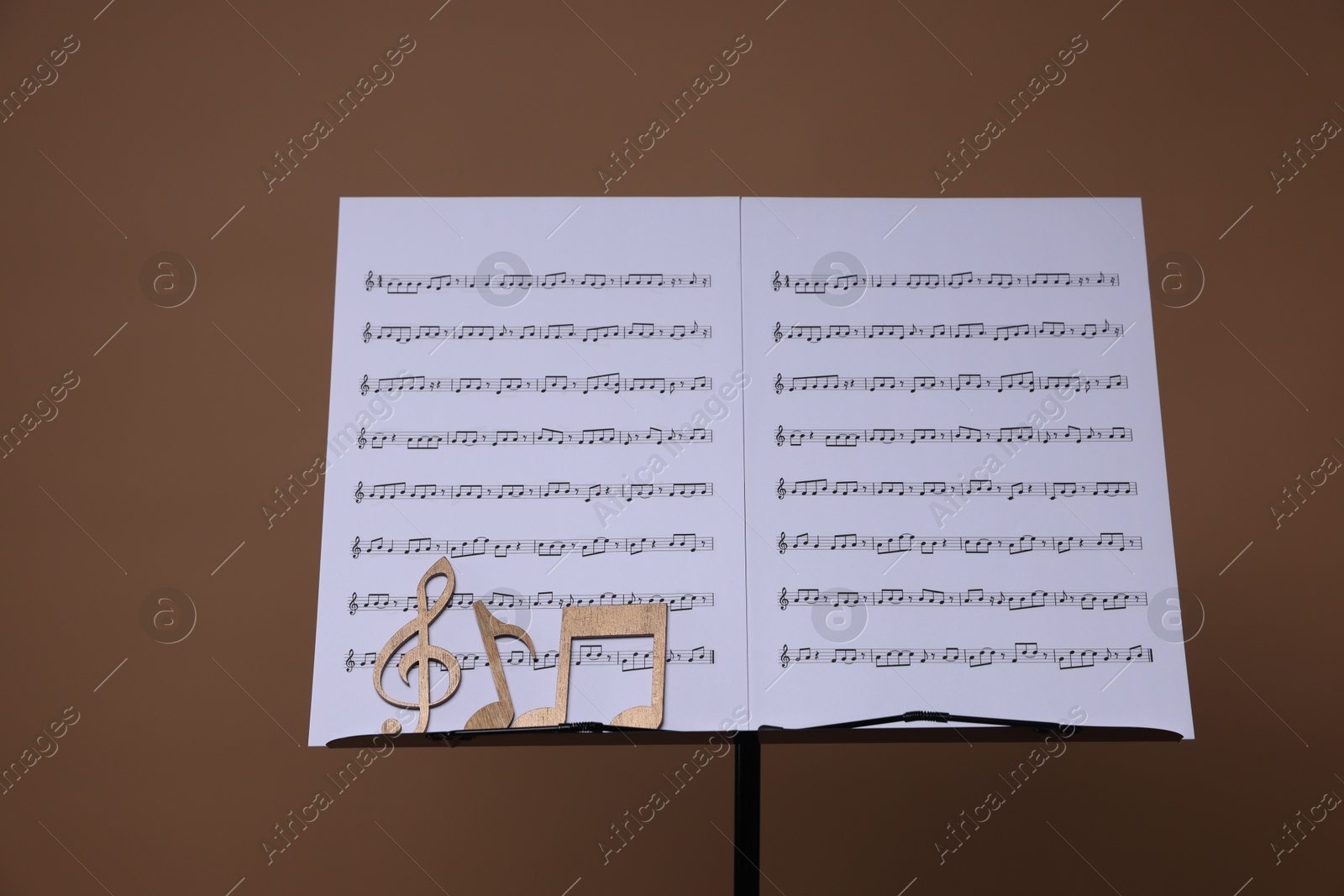 Stand with music sheets and wooden notes on dark beige background Photo of Stand with music sheets and wooden notes on dark beige background