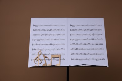 Photo of Stand with music sheets and wooden notes on dark beige background