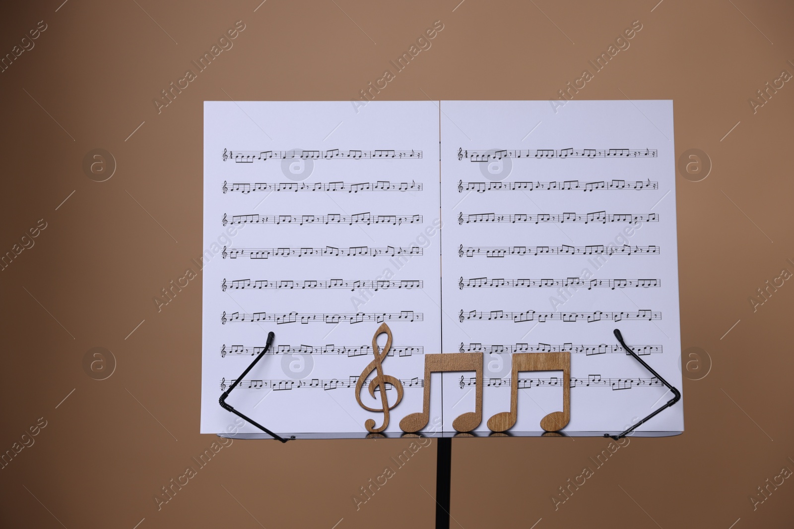 Stand with music sheets and wooden notes on dark beige background Photo of Stand with music sheets and wooden notes on dark beige background