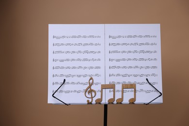 Photo of Stand with music sheets and wooden notes on dark beige background