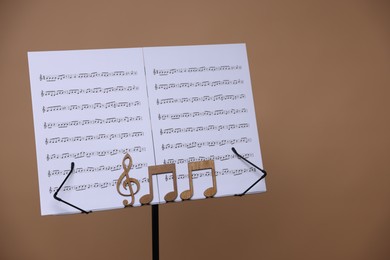 Photo of Stand with music sheets and wooden notes on dark beige background, space for text