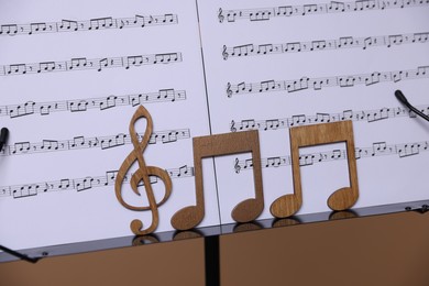 Photo of Stand with music sheets and wooden notes on dark beige background, closeup