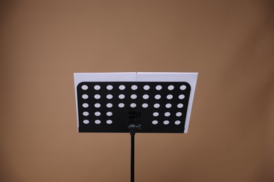 Photo of Stand with music sheets on dark beige background