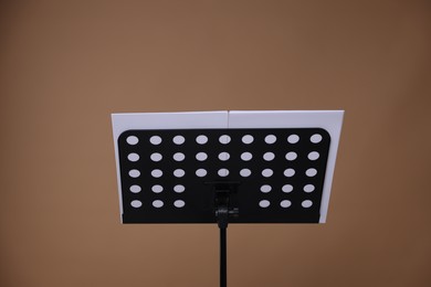 Photo of Stand with music sheets on dark beige background