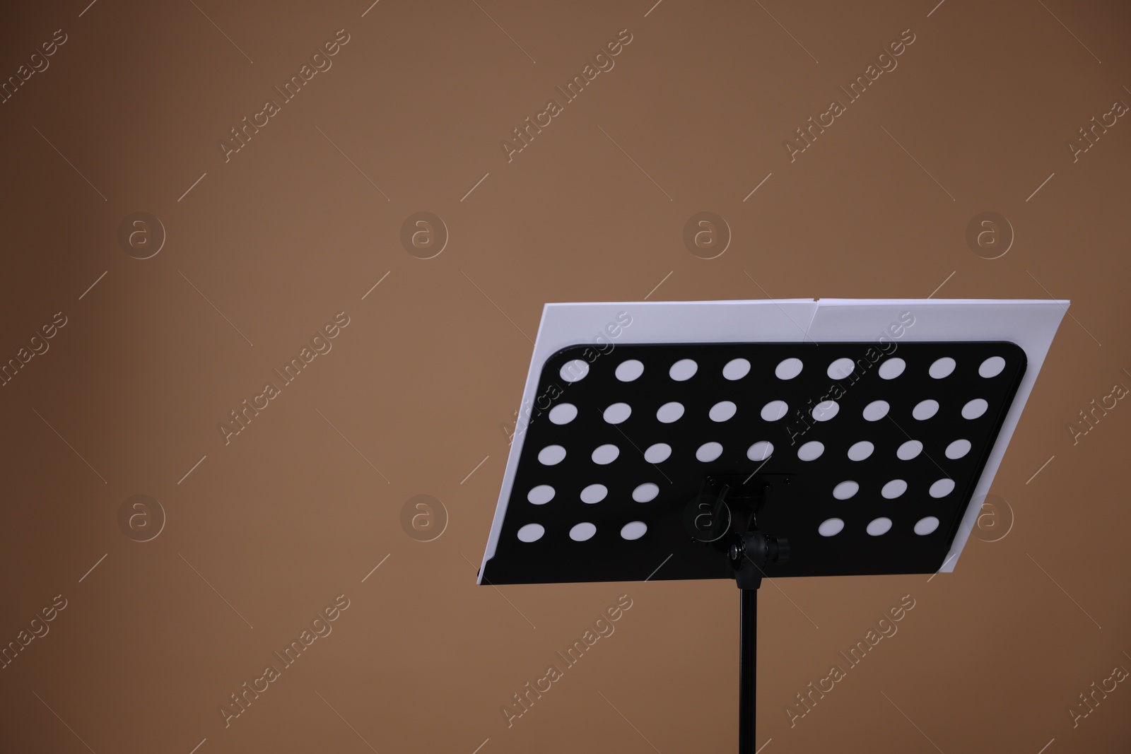Stand with music sheets on dark beige background, space for text Photo of Stand with music sheets on dark beige background, space for text