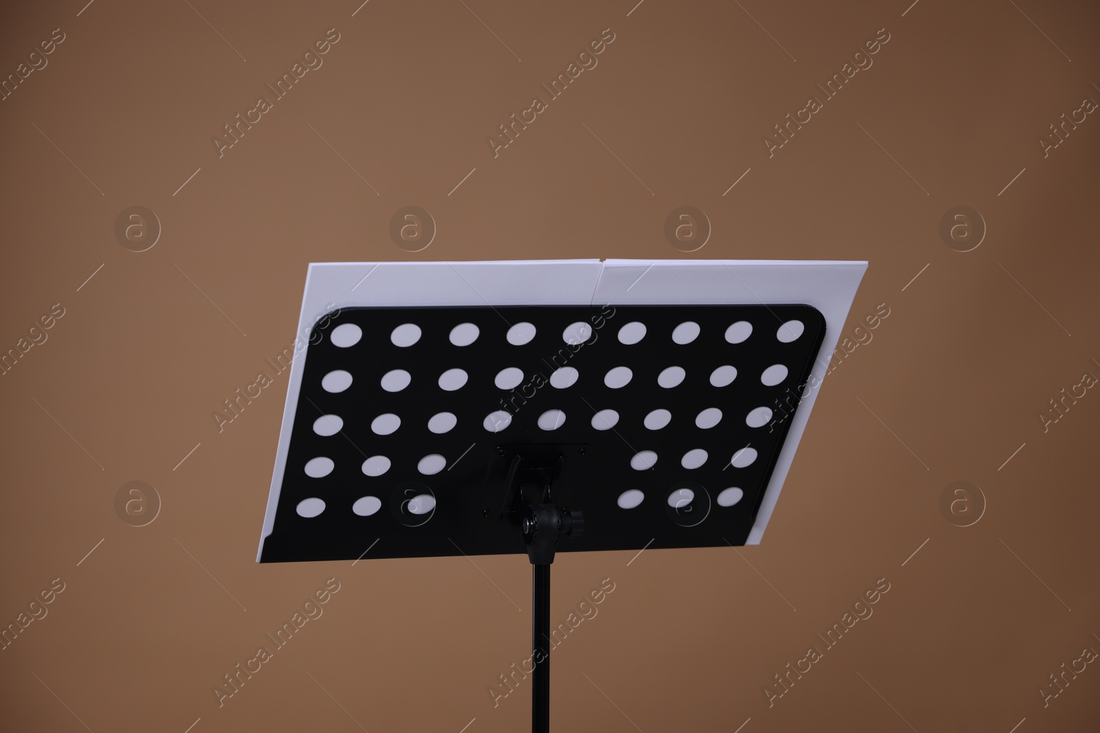 Stand with music sheets on dark beige background Photo of Stand with music sheets on dark beige background