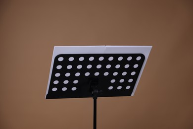 Photo of Stand with music sheets on dark beige background