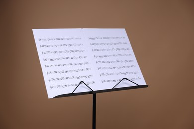 Photo of Stand with music sheets on dark beige background