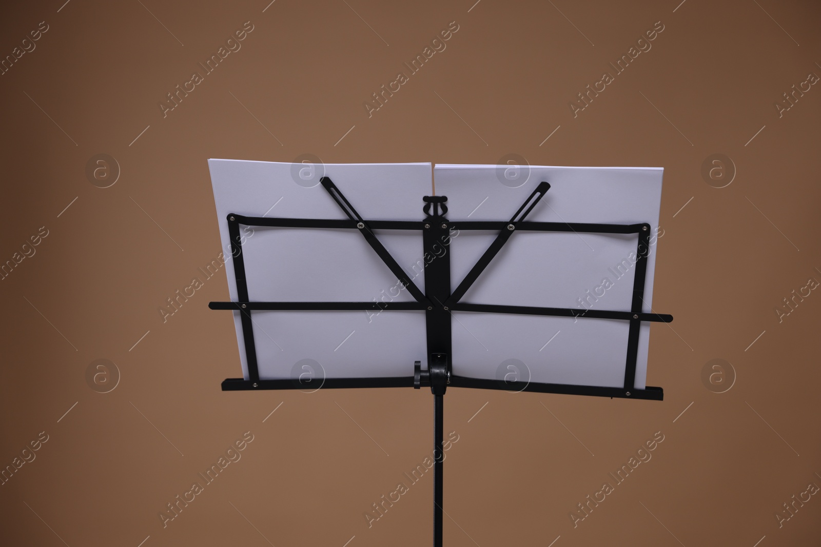 Stand with music sheets on dark beige background Photo of Stand with music sheets on dark beige background