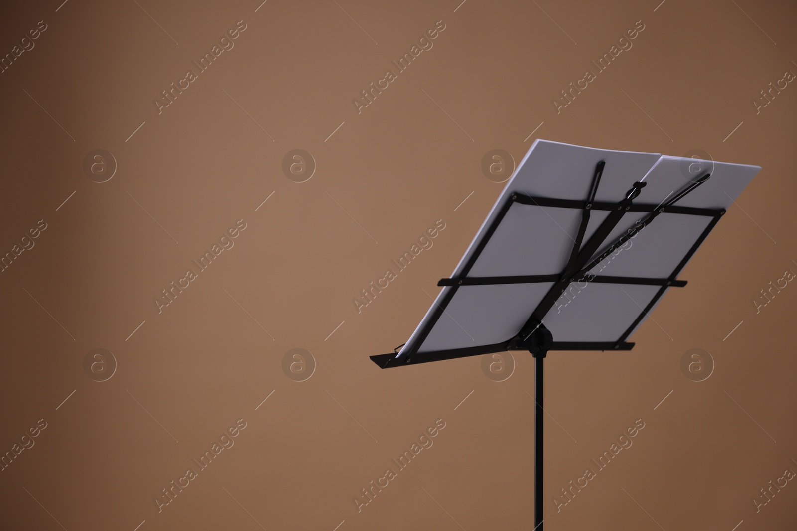 Stand with music sheets on dark beige background, space for text Photo of Stand with music sheets on dark beige background, space for text