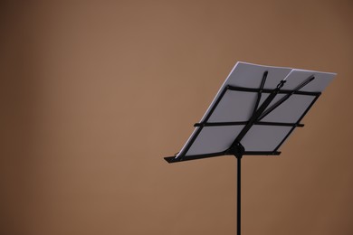 Photo of Stand with music sheets on dark beige background, space for text