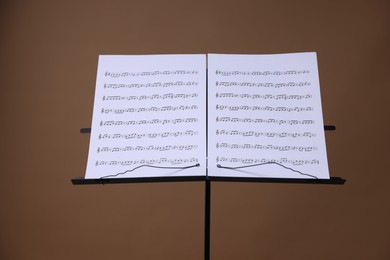 Photo of Stand with music sheets on brown background