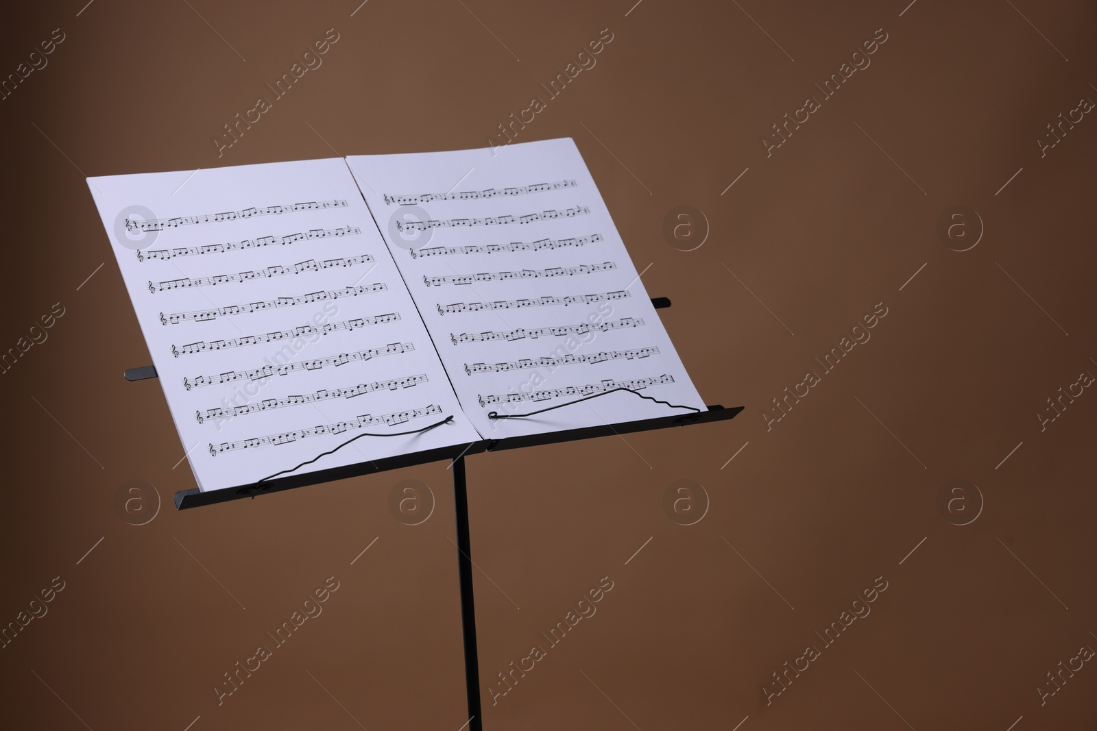 Stand with music sheets on brown background, space for text Photo of Stand with music sheets on brown background, space for text