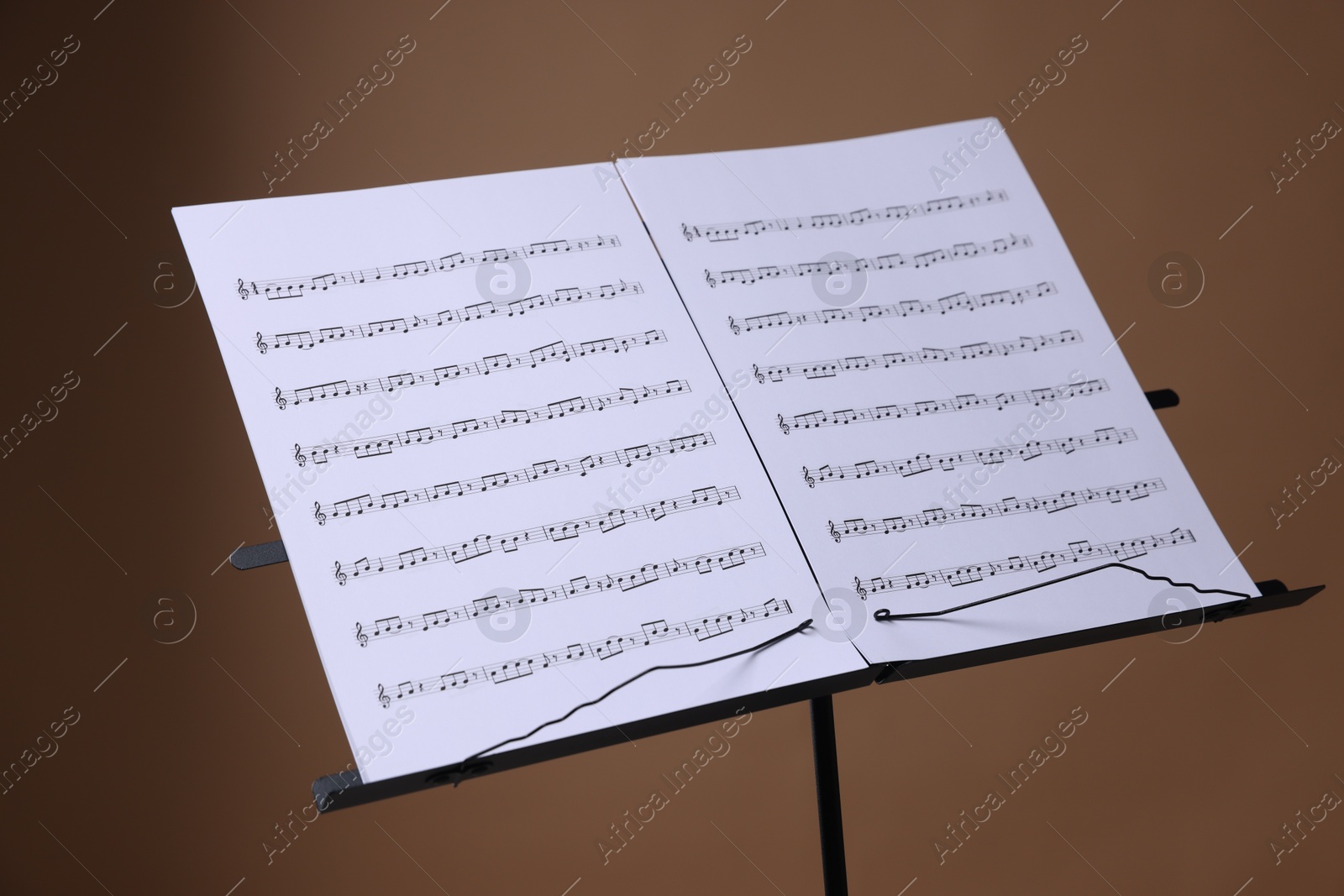 Stand with music sheets on brown background, closeup Photo of Stand with music sheets on brown background, closeup